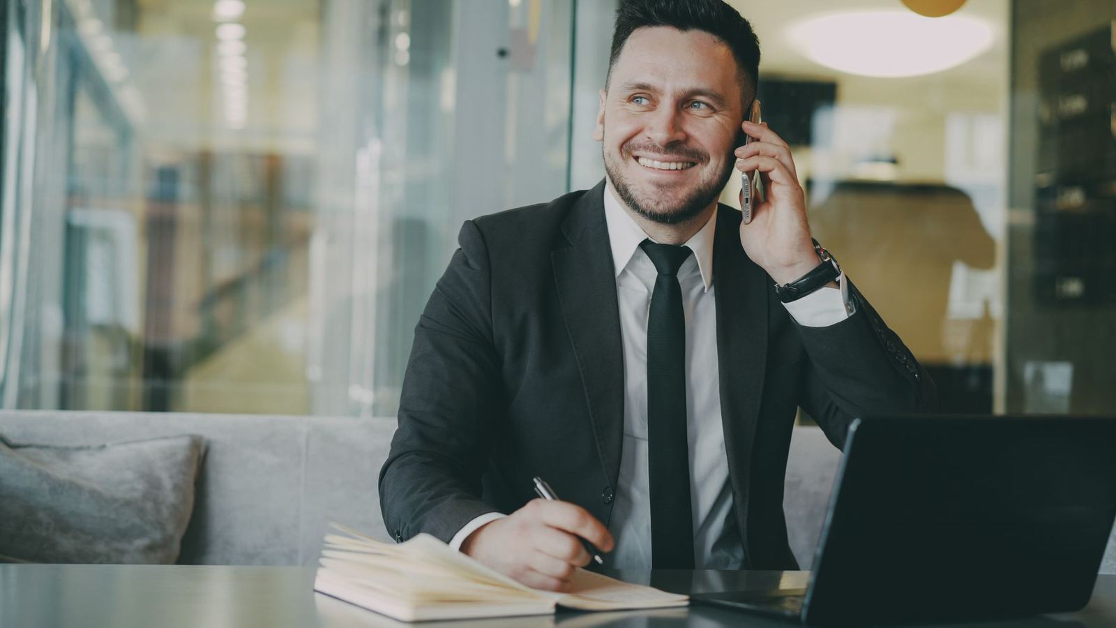 A man in a suit taking a call at a desk