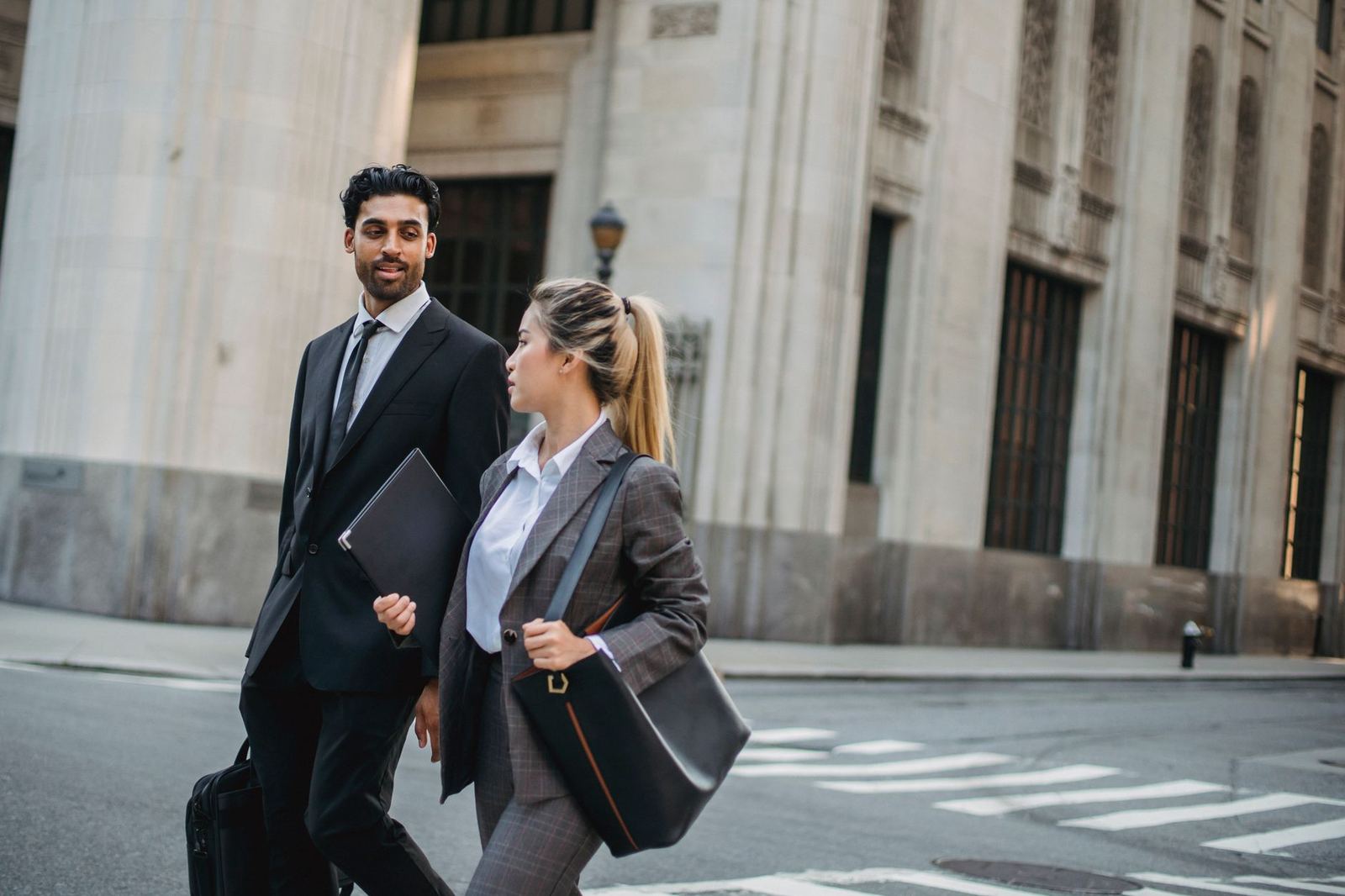 Two colleagues walking through a city street carrying a briefcase