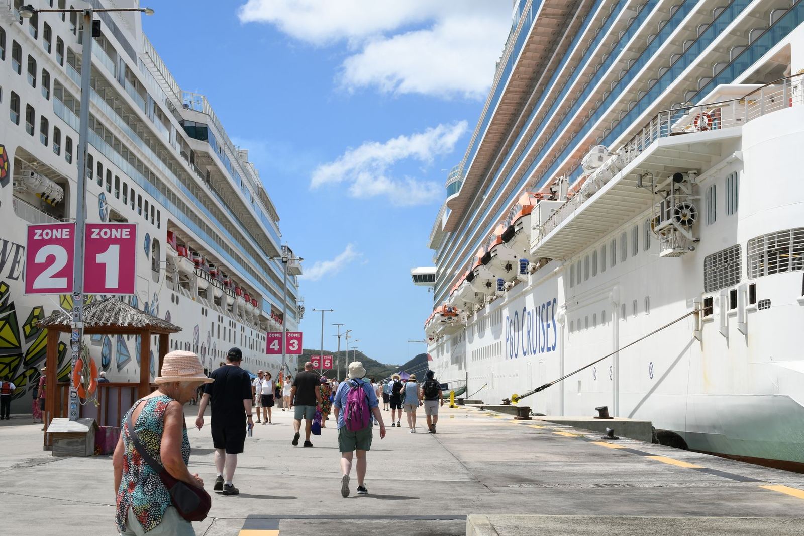 Passengers walking along a pier beside a cruise ship