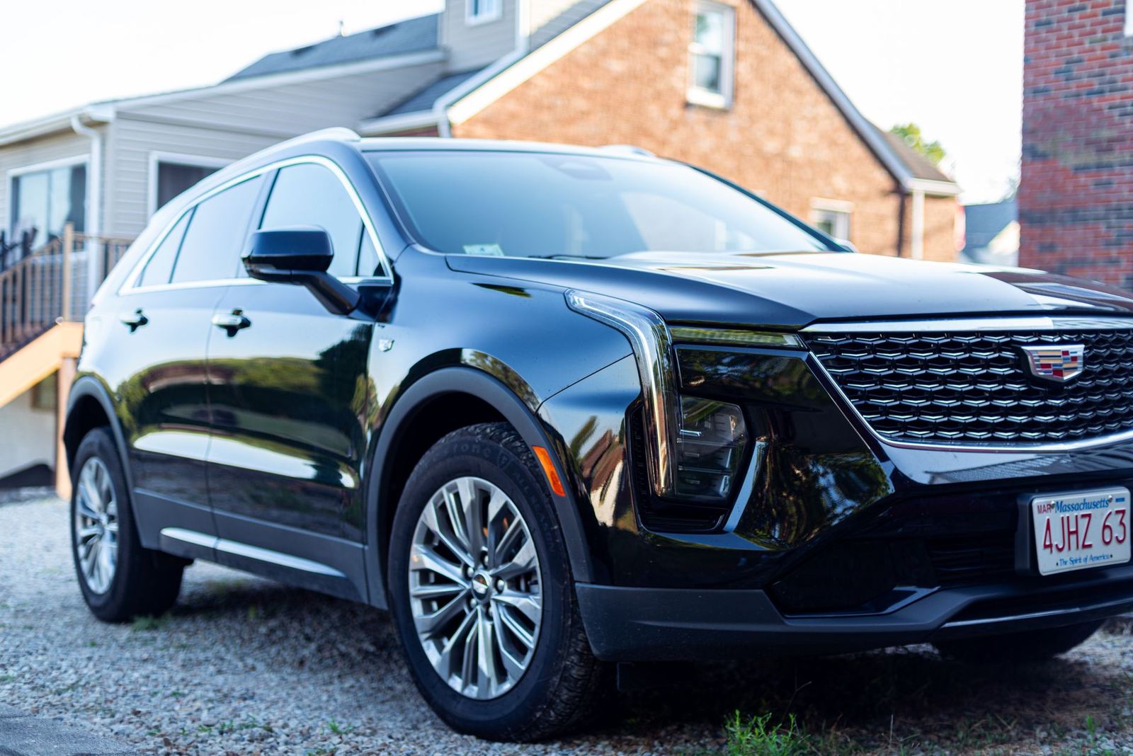 A new black Cadillac SUV parked in front of a brick house